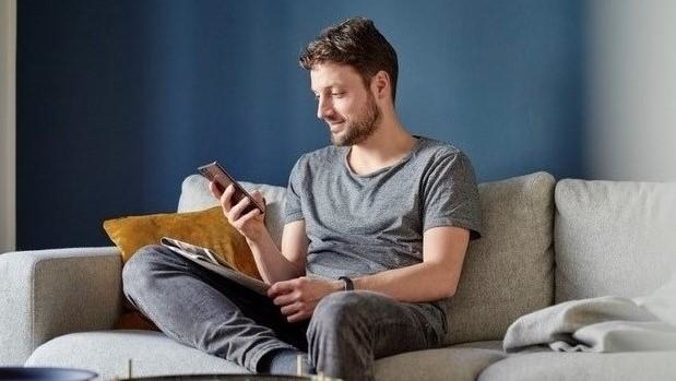 Man sitting i a sofa looking at his mobile.