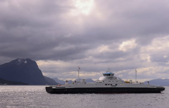 Bilferje på en fjord med fjell i bakgrunnen