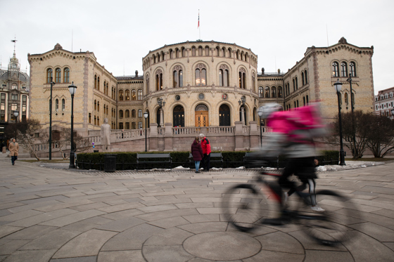 En mann på sykkel passerer Stortinget