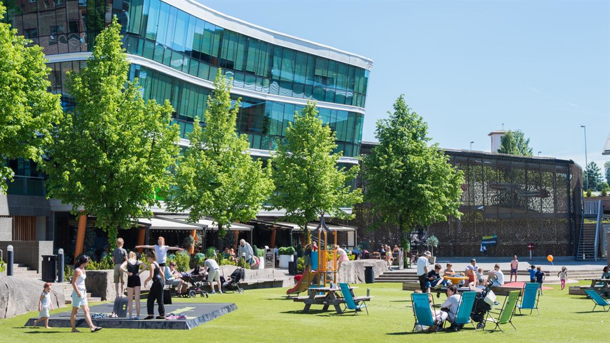 Torg, lekeplass og møteplass omkranset av serveringssteder og butikker.