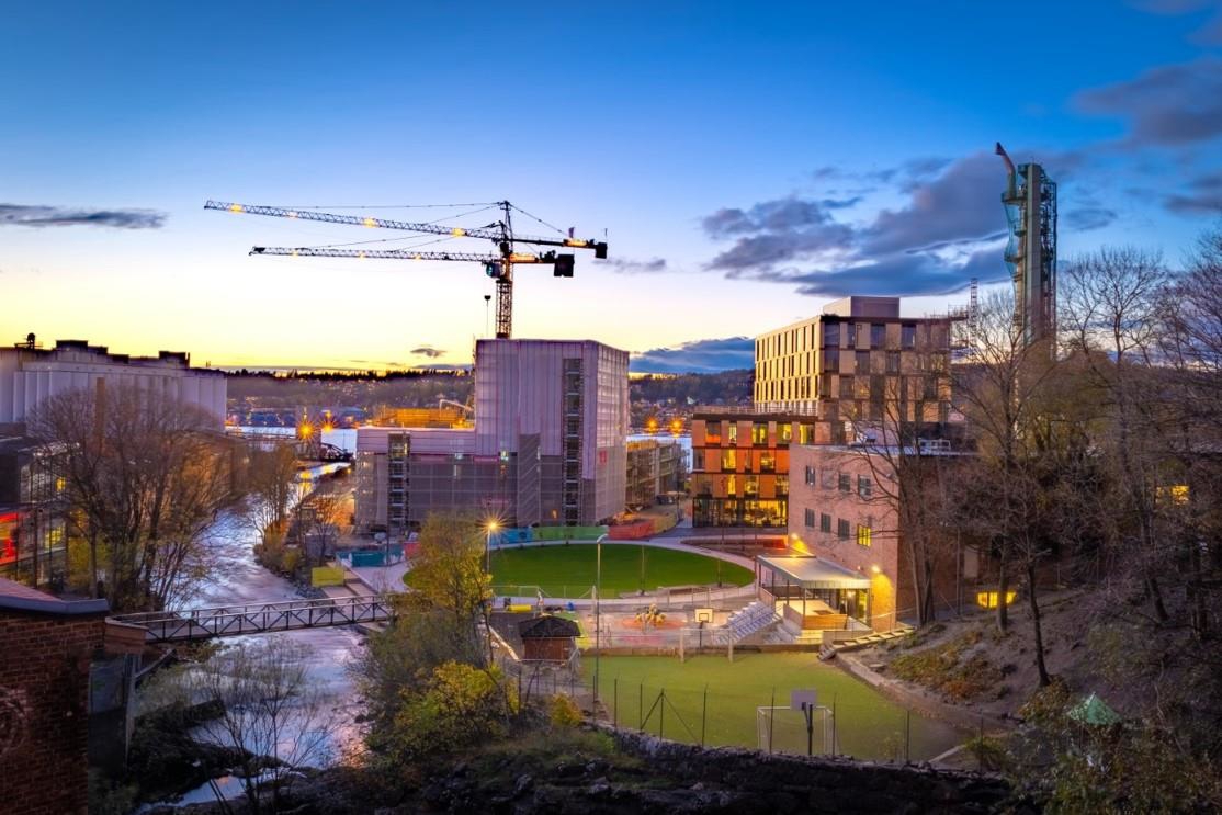 Kveldsstemning med elv, boliger, kontorer, skole og kulturscener på Verket, tidligere industriområde.