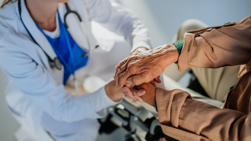 Health personnel holding hands to an elderly person