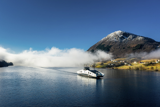 Ferja MS Nesvik på en fjord med fjell i bakgrunnen