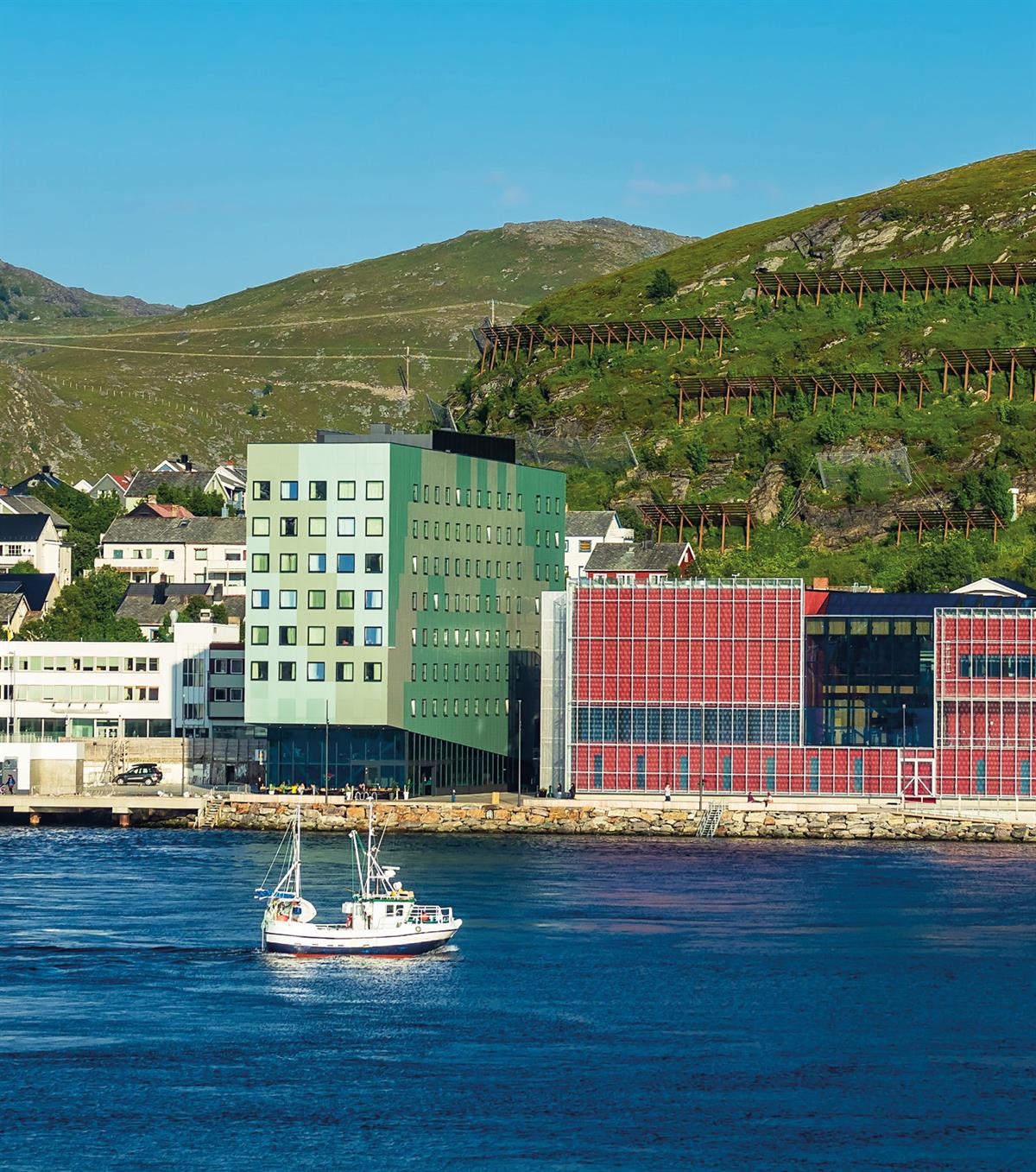 Hammerfest sett fra sjøen med sjark i forgrunnen, bygninger på land og fjellsiden bak. Foto: Colourbox.