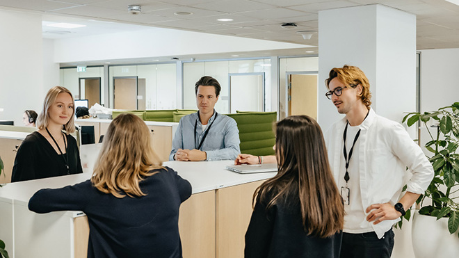 Bilde av fem kollegaer som står og snakker sammen.