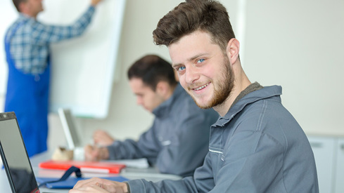 Bilde av fagskoleelev som  sitter i klasserom med PC