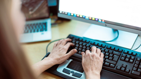 Nærbilde av hender som skriver på PC-tastatur