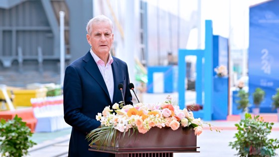 Prime Minister Støre behind a speech stand on stage. A ship in the background.