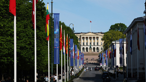 Bilde av Karl Johans gate pyntet med flagg og Nato-banner. Slottet i enden av gaten. 